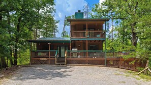 Eine zweistöckige Holzhütte mit Balkon, umgeben von Bäumen.