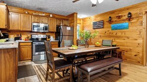 A wooden interior with a kitchen, dining table, chairs, and a bench. - Dream Chaser by Avantstay Hot Tub + Arcade + Porch Swing Mountain Views, Minutes to the Parkway (Sevierville)