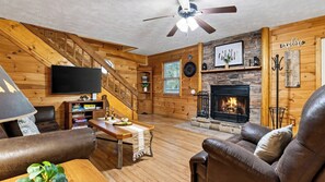 A cozy living room with a fireplace, wooden walls, a television, and leather furniture. - Dream Chaser by Avantstay Hot Tub + Arcade + Porch Swing Mountain Views, Minutes to the Parkway (Sevierville)