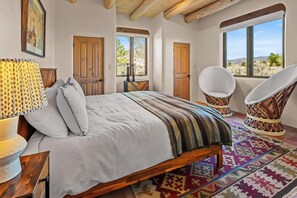 Ein Schlafzimmer mit einem Bett, zwei Stühlen, einem Teppich und einem Fenster mit Blick.