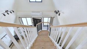 En trætrap med hvide gelændere fører op til en platform med en dør og vinduer.