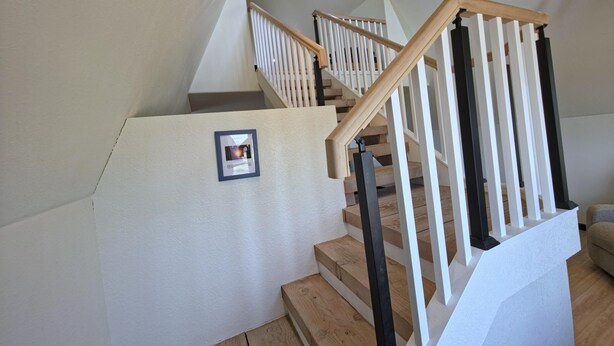 En trappe med trætrapper og hvide gelændere, der fører op til en etage.