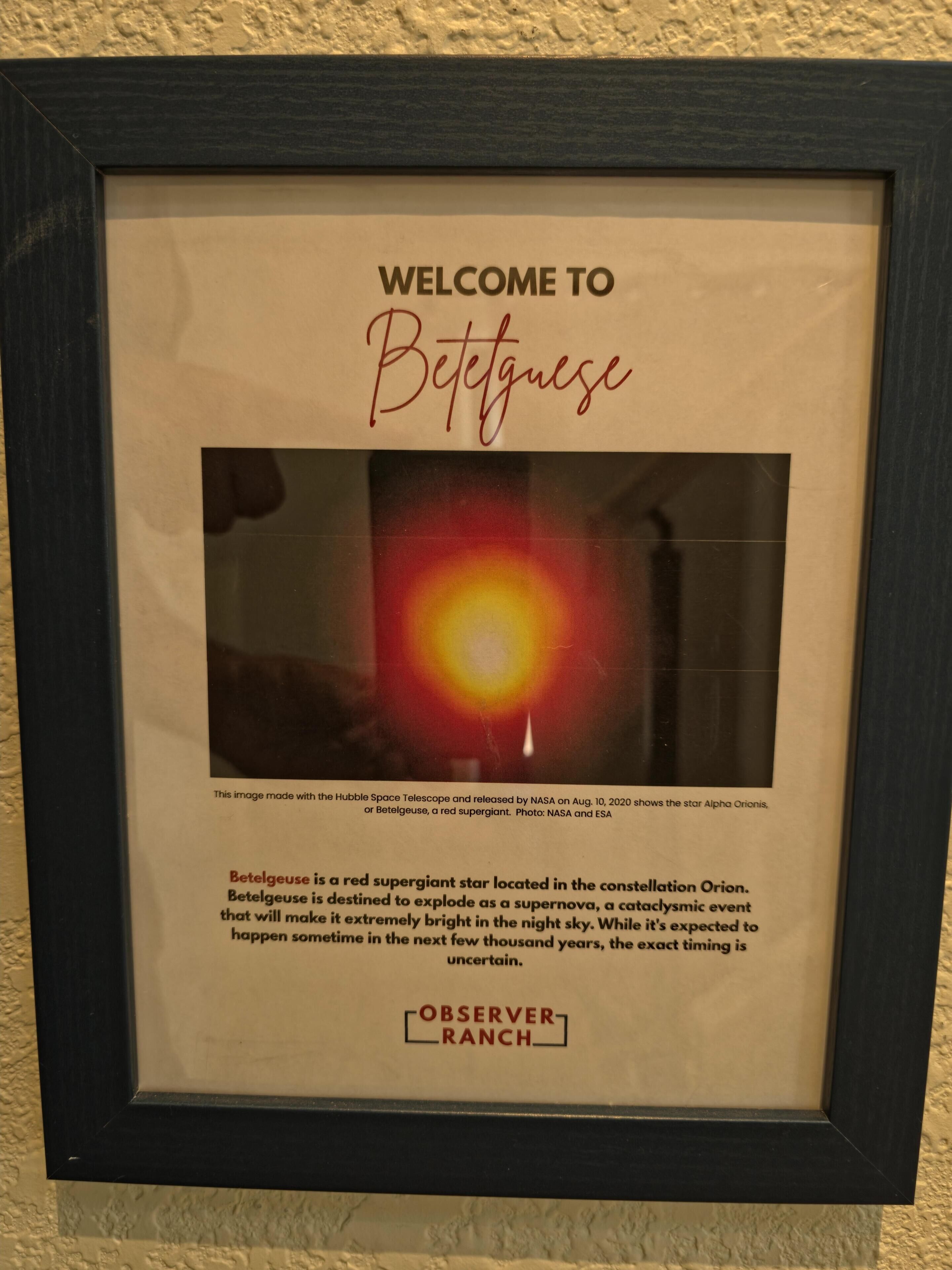 A framed welcome sign with a photograph of Betelgeuse, a red supergiant star.