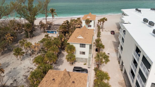 A beachfront property with a two-story building, a parking area, and a beach view. - Paradise on the Sea (Englewood)