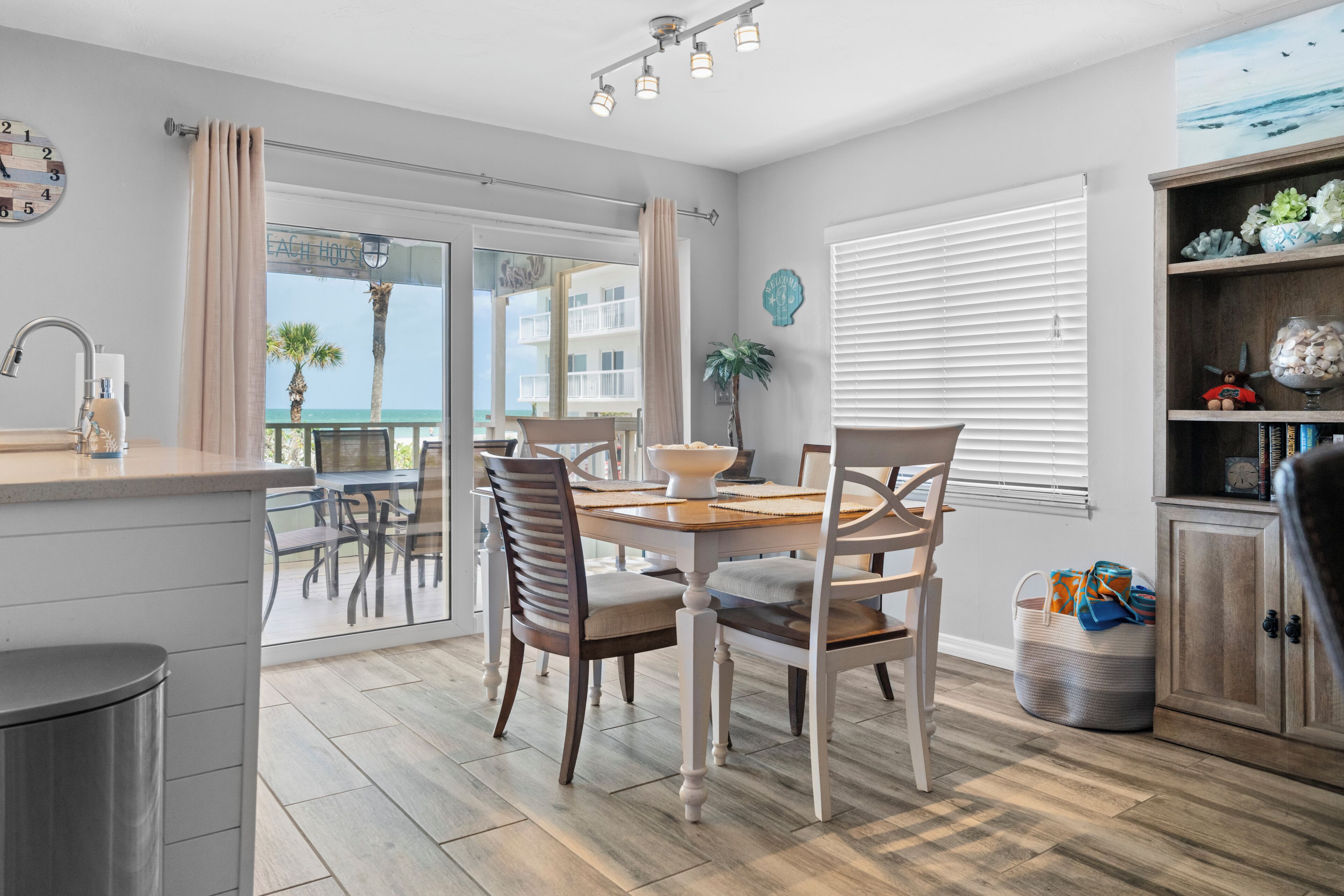 A modern kitchen with a dining area, a view of the ocean, and a balcony.