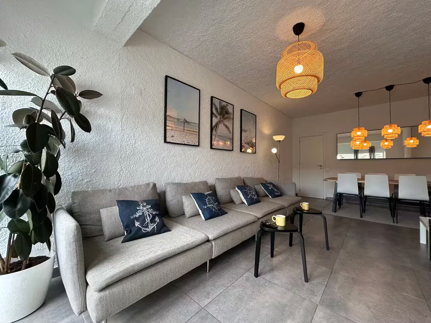 A modern living room with a sofa, coffee table, and a dining area with chairs and a table.