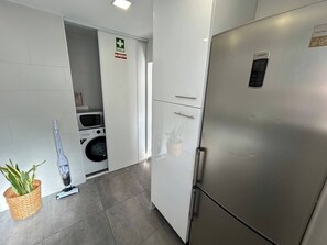 Eine kompakte Küche mit einem Edelstahlkühlschrank, einer Mikrowelle und einer Waschmaschine.
