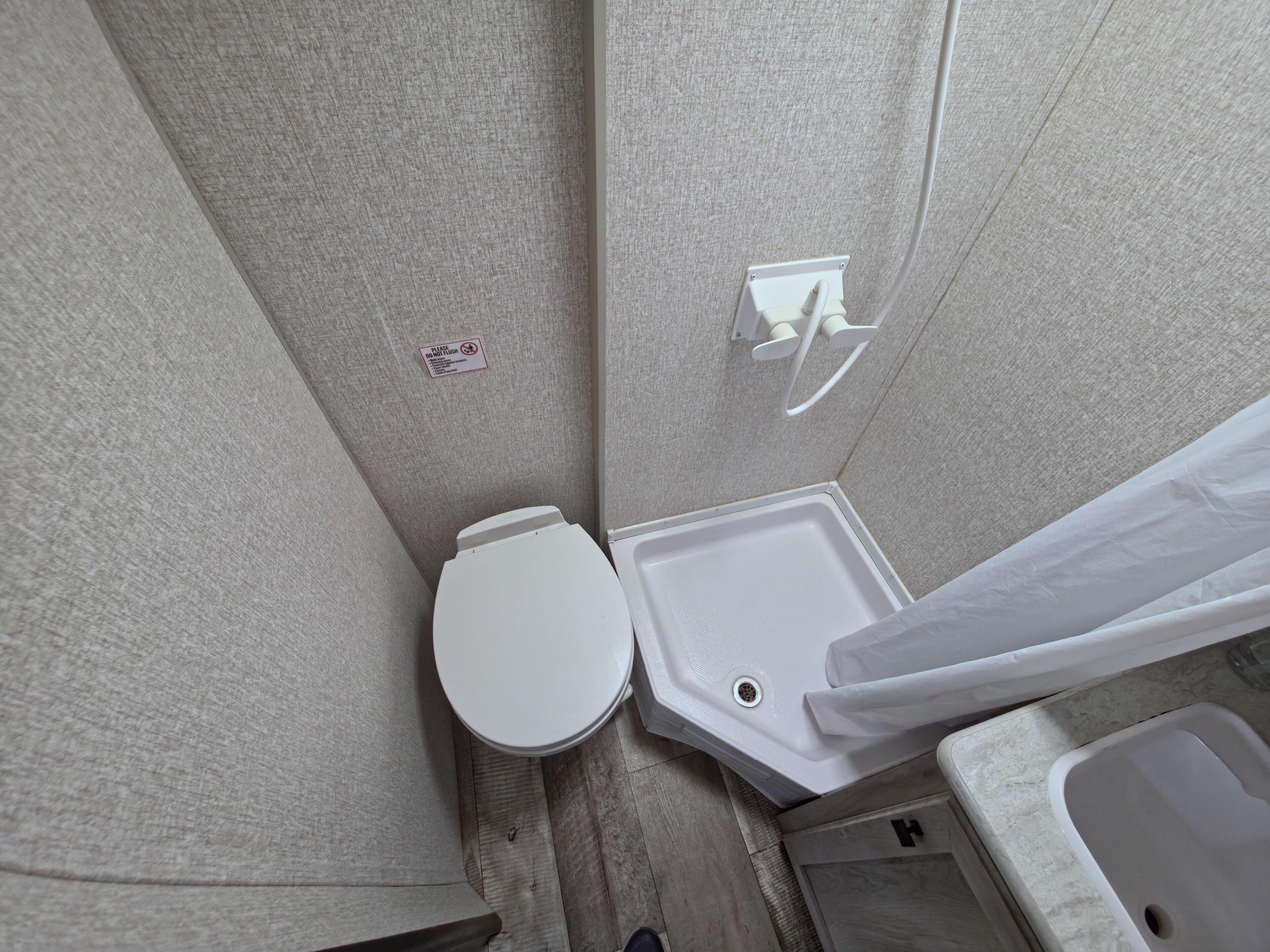 Ein Badezimmerbereich mit Toilette, Duschkabine und kleinem Waschbecken.