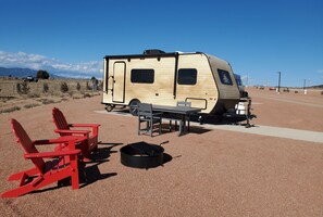 Un véhicule récréatif avec une table et des chaises installées sur une surface recouverte de gravier.