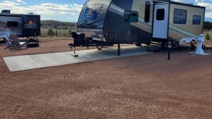 Una vehículo recreativo con la marca 'Ranch', equipado con una bomba de agua, ubicado en un camping con cielo despejado.