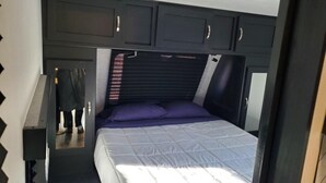 Un dormitorio acogedor con cama, cabecera y armarios empotrados.