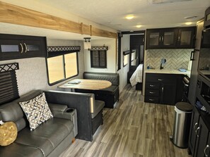 En kompakt autocamper indretning med kitchenette, siddeområde og et lille spisebord.