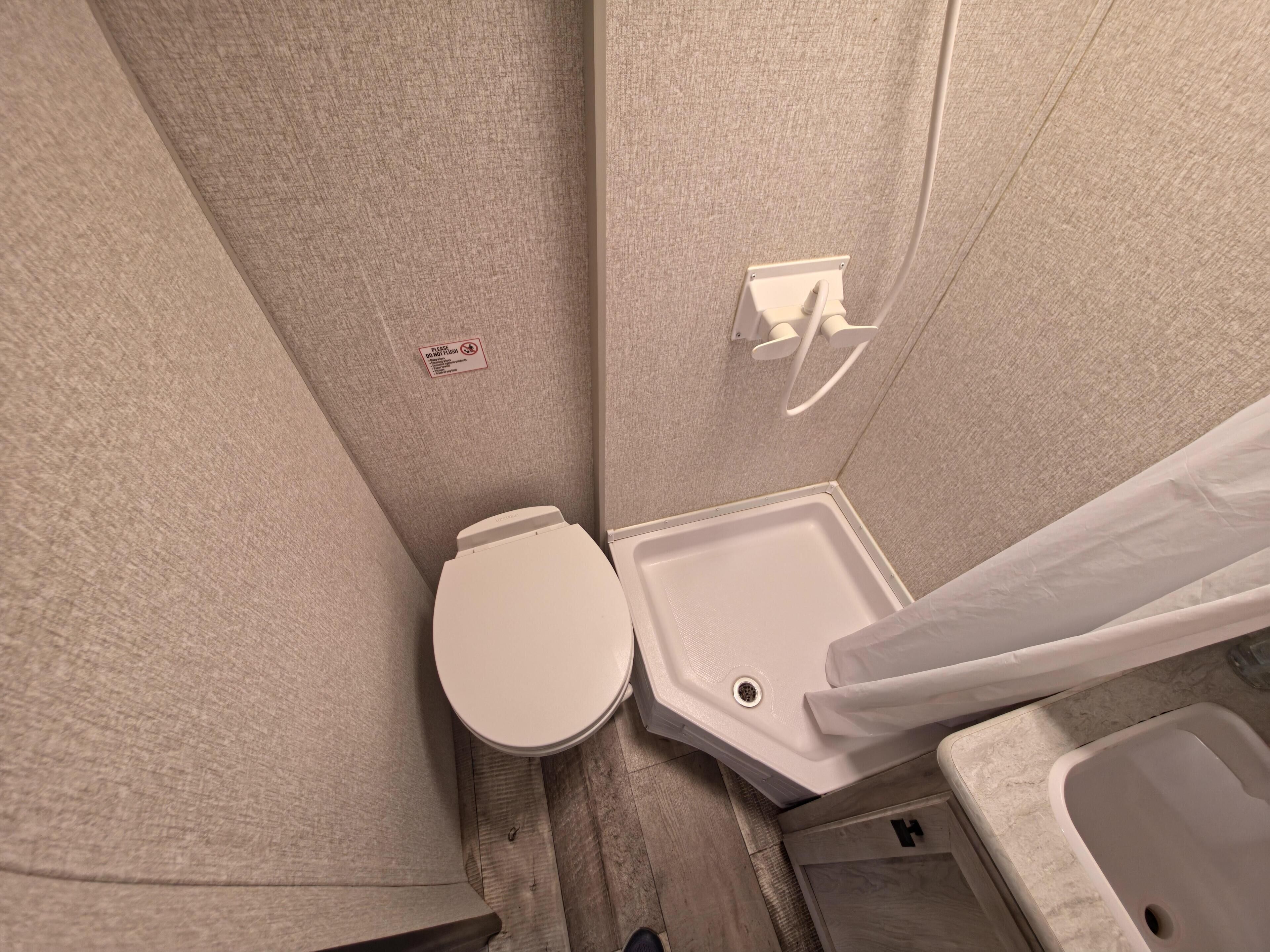 A bathroom with a toilet, a sink, and a shower area.