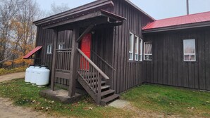 Una baita in legno con una porta rossa, una scala che conduce all'ingresso e un piccolo portico.