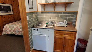 Una cucina compatta con piano cottura, lavello e lavastoviglie, pensili in legno e un piccolo bancone.
