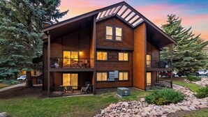 A multi-story wooden building with balconies, outdoor seating, and a well-maintained garden. - Cabriolet Chalet by Avantstay King Suite + Bunk Loft + BBQ Deck Walk to Lift + Pool Access (Park City)
