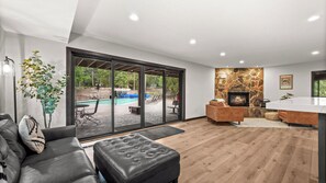 Ein modernes Wohnzimmer mit Kamin, Blick auf einen Pool und einer gemütlichen Sitzecke.