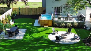 A backyard with a hot tub, patio furniture, and a fire pit. - Stay at Bree's Retreat! Spacious 5BR Pet-Friendly- 5 Mins to Beach-Large Yard! (South Haven)