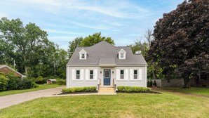 Una casa a un piano con un portico anteriore, un piccolo giardino e un vialetto che conduce all'ingresso.