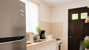 A compact kitchen with a refrigerator, a coffee maker, and a sink. - Private 2-bedroom apartment in the heart of Cancun (pet-friendly) (Cancún)