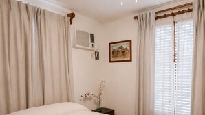 A bedroom with a bed, a ceiling fan, an air conditioning unit, a framed picture, and a window with curtains. - Private 2-bedroom apartment in the heart of Cancun (pet-friendly) (Cancún)