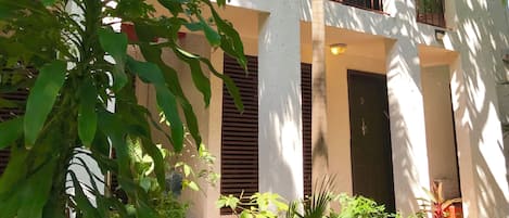A building with multiple arches and a balcony, surrounded by lush greenery.