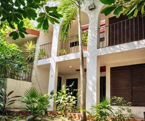 A multi-story building with balconies, surrounded by various plants and trees. - Private 2-bedroom apartment in the heart of Cancun (pet-friendly) (Cancún)