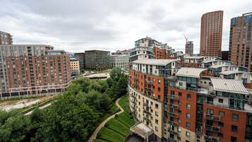 A high-rise residential building with multiple balconies, a landscaped garden, and a view of the surrounding urban area.