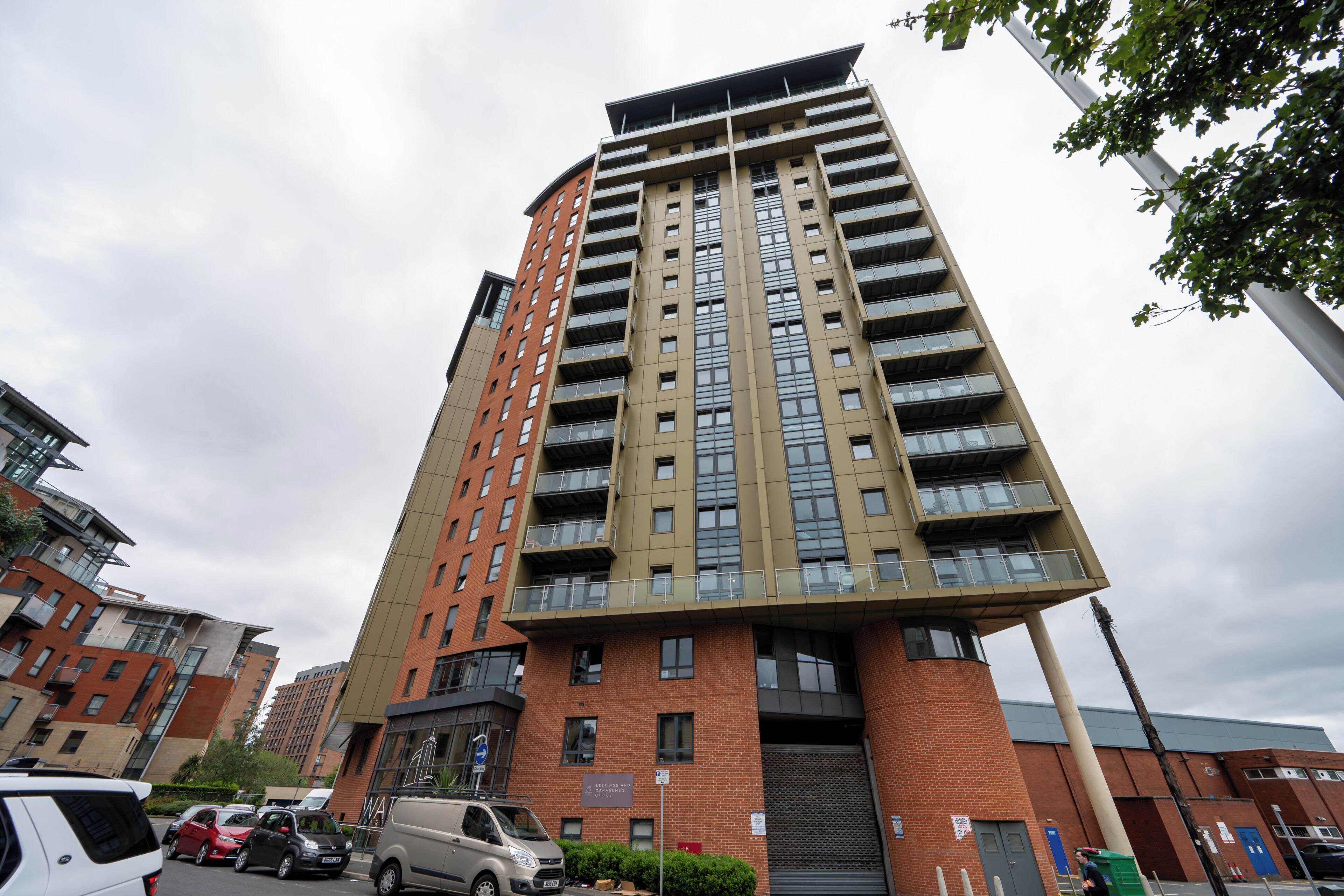 A multi-story building with a modern architectural design, featuring a mix of brick and glass facades, and a prominent vertical structure.