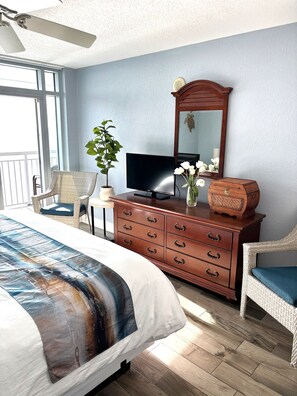 A hotel room with a bed, a dresser, a television, a chair, and a potted plant. - Unobstructed Oceanfront View! 3BR, 3BA, Grand Atlantic Resort, 20th Floor Condo (Myrtle Beach)
