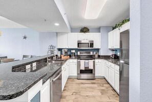 Een moderne keuken met witte kasten, roestvrijstalen apparatuur en een granieten aanrecht.