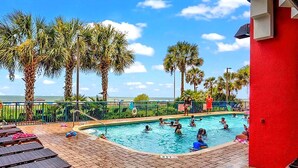 A swimming pool with people, palm trees, and a view of the ocean. - Unobstructed Oceanfront View! 3BR, 3BA, Grand Atlantic Resort, 20th Floor Condo (Myrtle Beach)