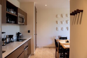 Eine moderne Küche mit Edelstahlgeräten, ein Essbereich mit Tisch und Stühlen sowie eine Wand mit dekorativen Masken.