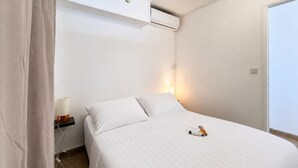 Um quarto com uma cama, ar condicionado, luminária de cabeceira e uma porta.