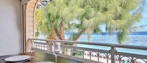 A dining area with a view of the sea and trees.