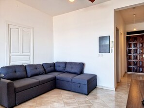A modern living room with a sectional sofa, a wooden door, and a tiled floor. - Le Mosala 2 - Climatisation - Vue mer (Saint-Leu)