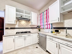 A kitchen with white cabinets, a gas stove, a dishwasher, and a colorful striped towel hanging on the wall. - Le Mosala 2 - Climatisation - Vue mer (Saint-Leu)