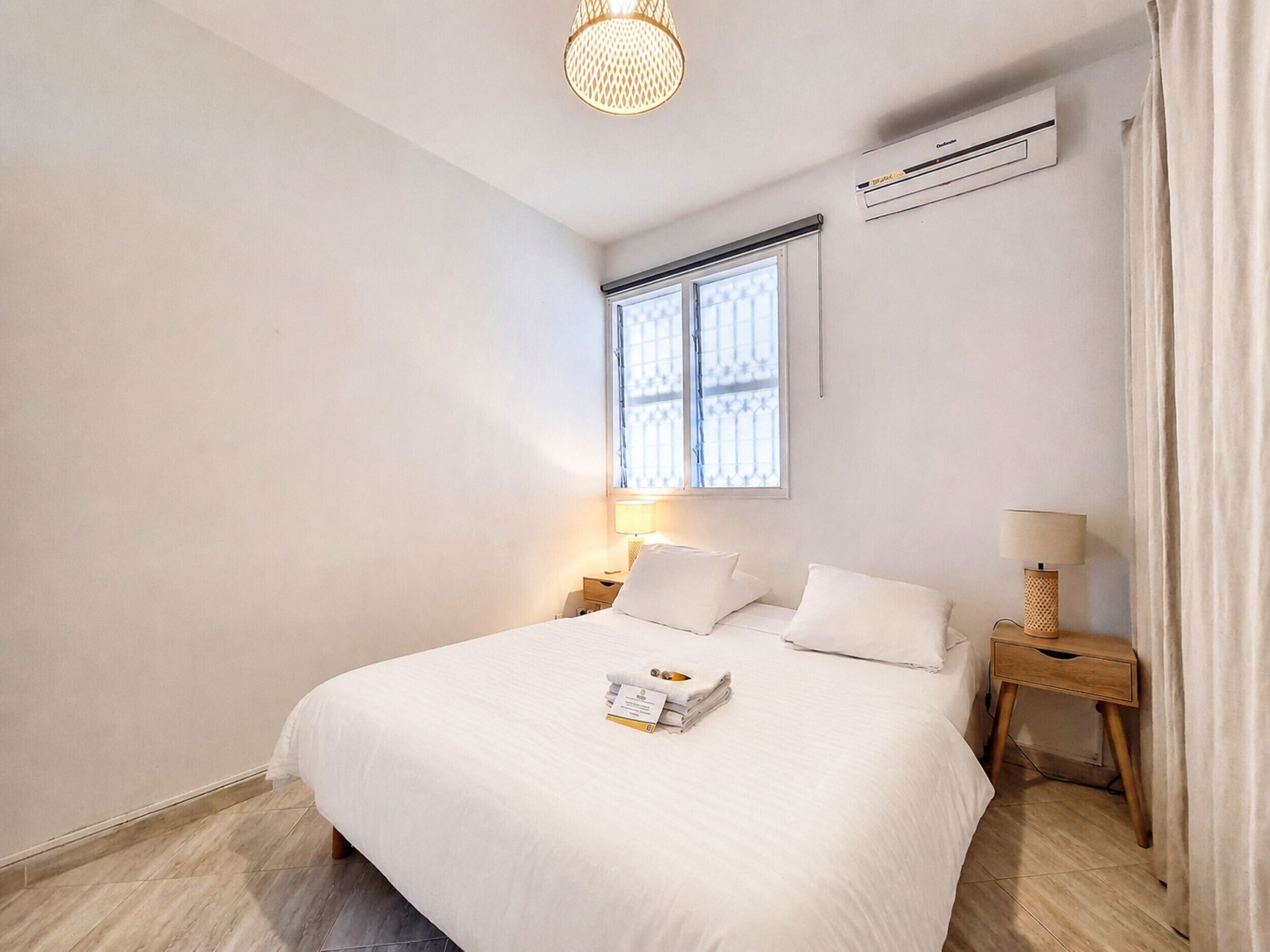 Une chambre d’hôtel équipée d’un lit, de tables de chevet, d’une fenêtre et d’un appareil de climatisation.