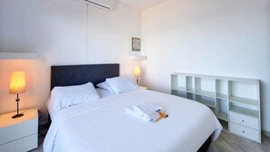 Ein Hotelzimmer mit einem Bett, Nachttischlampen, einer Klimaanlage, einem Deckenventilator und einer festen Regaleinrichtung.