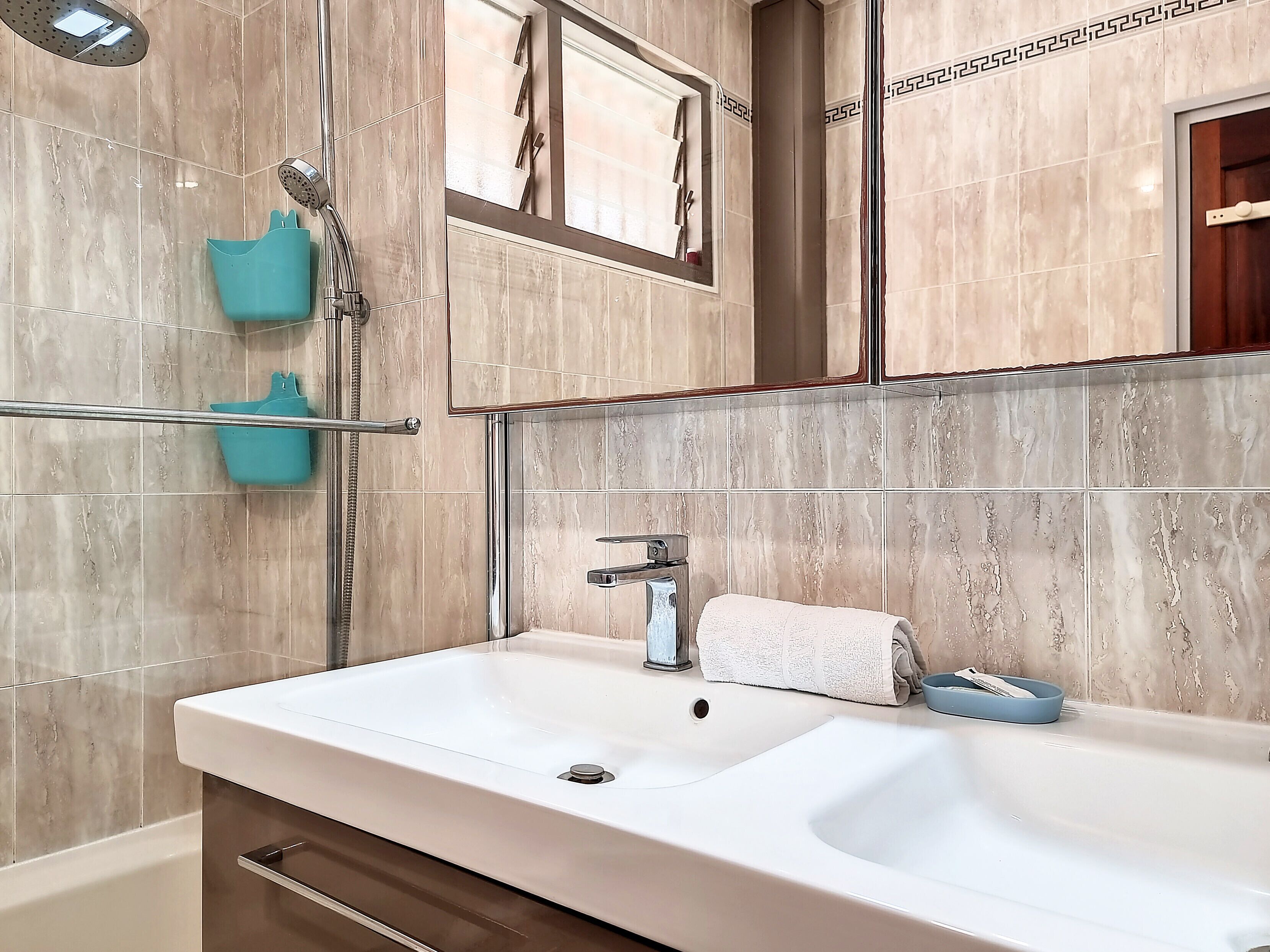 A modern bathroom with a large sink, a mirror, and a shower.