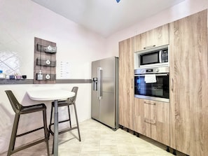 Una cocina moderna con refrigerador de acero inoxidable, horno doble y armarios de madera.
