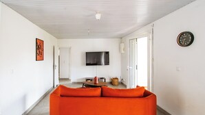 Ein modernes Wohnzimmer mit einer Couch, einem Flachbildfernseher und einem Essbereich.