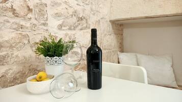 A table with a bottle of wine, a glass, a bowl of lemons, and a potted plant.