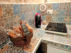Eine Küche mit gefliestem Fliesenspiegel, einer Kaffeemaschine, einem Brotkorb und einer Brotkiste.
