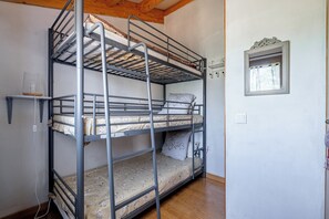 Ein Etagenbett mit drei Schlafstellen, ein Fenster mit Zierrahmen und eine Steckdose an der Wand.