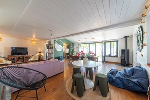 Un amplio salón con sofá, sillas, televisor y una mesa de comedor.