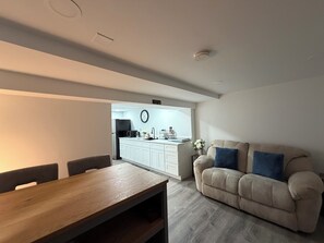 Ett modernt vardagsrum med ett matbord i trä och en beige soffa med blå kuddar.