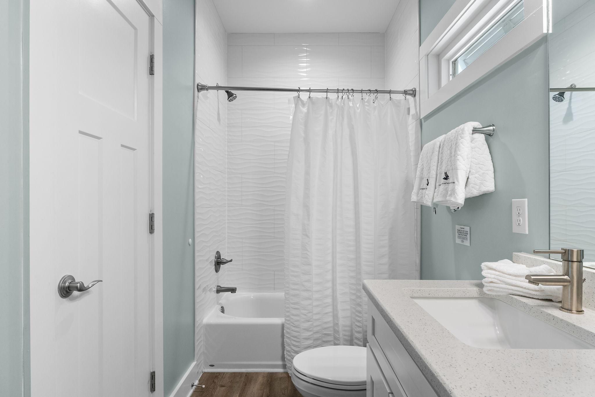 A bathroom with a shower, toilet, and sink.
