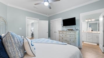 Ein Schlafzimmer mit Bett, Kommode, Schminktisch und Deckenventilator.