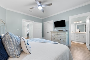 Un dormitorio con cama, cómoda, tocador y ventilador de techo.